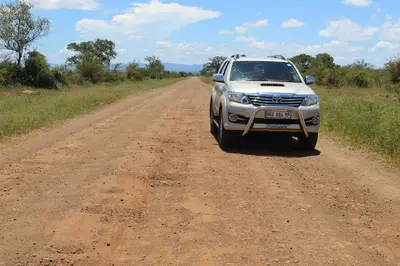 a white suv driving down a dirt road at Steenbok Guesthouse in Steenbok