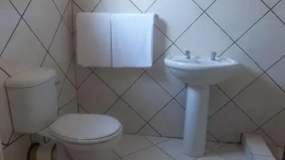 a white bathroom with a toilet and a sink at Steenbok Guesthouse in Steenbok