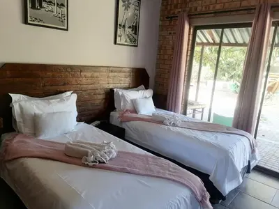 two beds sitting next to each other in a bedroom at Sol & Sombra Guesthouse in Komatipoort