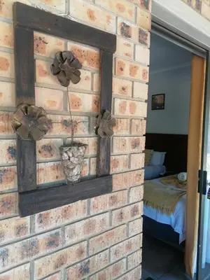 a brick wall with a mirror and bows on it at Sol & Sombra Guesthouse in Komatipoort