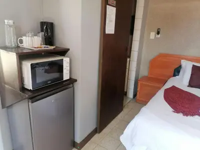 a room with a bed and a microwave on a refrigerator at Sol & Sombra Guesthouse in Komatipoort