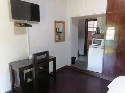 a kitchen with a table and a microwave and a refrigerator at Sol & Sombra Guesthouse in Komatipoort