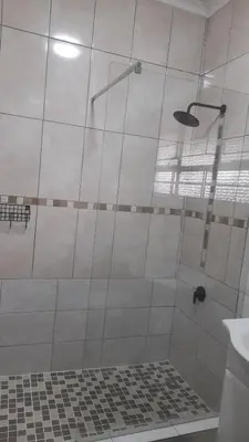 a bathroom with a shower with a glass door at Sol & Sombra Guesthouse in Komatipoort