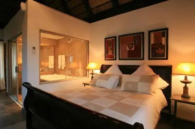 a bedroom with a bed with two lamps and a tub at Pensão Guest Lodge in Nelspruit