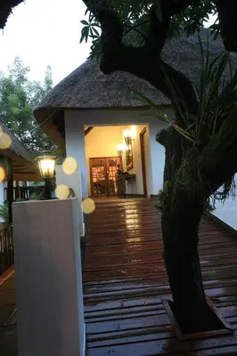a house with a wooden deck with a thatch roof at Pensão Guest Lodge in Nelspruit