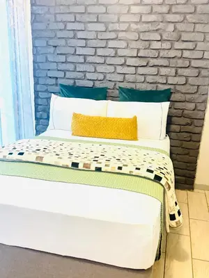 a bedroom with a white bed with a brick wall at Ts Group Africa furnished apartments - Marothwane Saturday Sebola in Pretoria