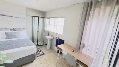 a bedroom with a bed and a desk and a window at Ts Group Africa furnished apartments - Marothwane Saturday Sebola in Pretoria