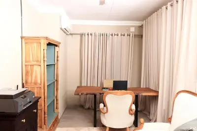 an office with a wooden desk and a chair at Maranzhe Villa in Musina