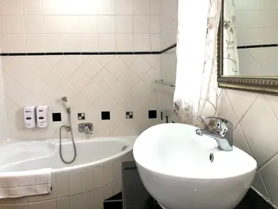 a white bathroom with a sink and a tub at Clubview Guest House in Centurion