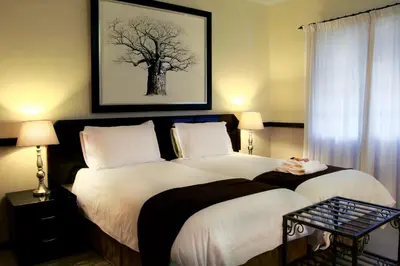 a bedroom with a bed with a tree picture on the wall at Clubview Guest House in Centurion