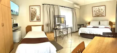 a hotel room with two beds and a table at Clubview Guest House in Centurion
