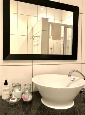 a bathroom with a white sink and a mirror at Clubview Guest House in Centurion