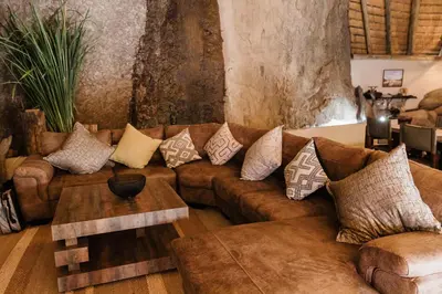 a living room with a brown couch with pillows at Timbila Game Lodge - Welcome to Land of Leopards and Buffalo in Phalaborwa