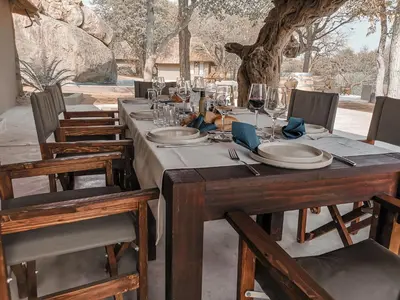 a long wooden table with plates and wine glasses at Timbila Game Lodge - Welcome to Land of Leopards and Buffalo in Phalaborwa