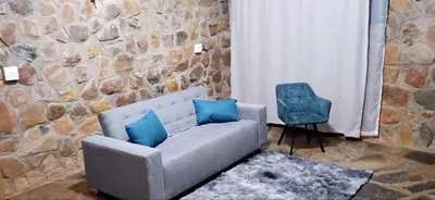 a living room with a couch and a blue chair at Risima Guest Lodge Hazyview in Numbi