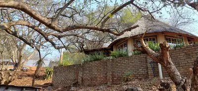 a house with a thatched roof on a brick wall at Risima Guest Lodge Hazyview in Numbi