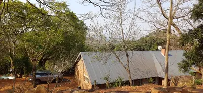 a truck parked in front of a building with trees at Risima Guest Lodge Hazyview in Numbi