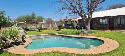 a swimming pool in a yard with a house at Die Windpomp Bosveld in Lephalale