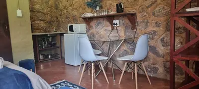 a room with two white chairs against a stone wall at Die Windpomp Bosveld in Lephalale
