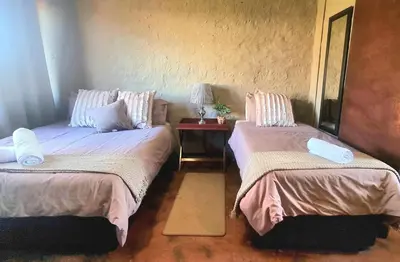 a room with two beds and a table with a lamp at Die Windpomp Bosveld in Lephalale
