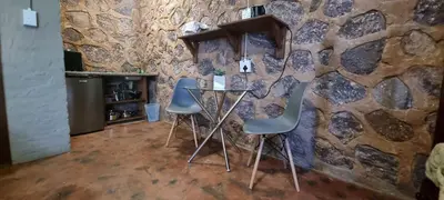 a table and two chairs in front of a stone wall at Die Windpomp Bosveld in Lephalale