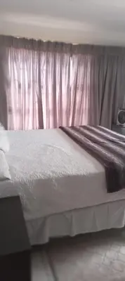 a bedroom with a white bed with a pink curtain at View in in Nelspruit