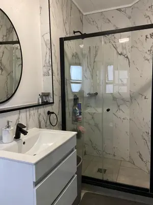 a white bathroom with a shower and a sink at The River-view in Midrand