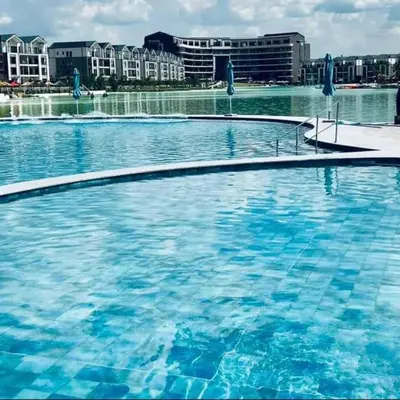 a large pool of blue water with buildings in the background at The River-view in Midrand