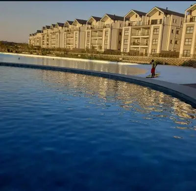 a person standing on a surfboard in front of a body of water at The River-view in Midrand