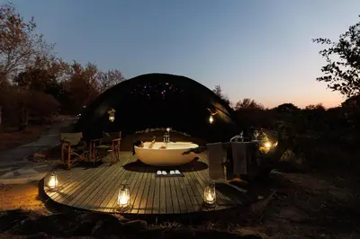 a tub sitting on a deck in a dome tent with lights at Garonga Safari in Makalali Game Reserve
