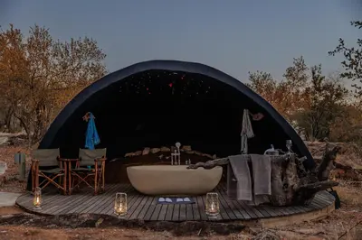 a tent with a bath tub and a table and chairs at Garonga Safari in Makalali Game Reserve