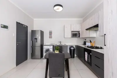 a kitchen with a table and a refrigerator at Smartz Apartment in Erand