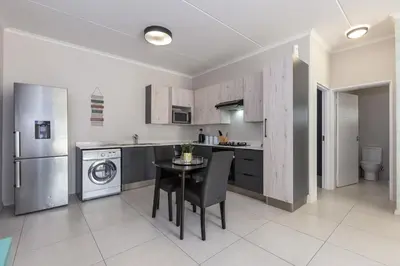 a kitchen with a table and a sink and a dishwasher at Smartz Apartment in Erand