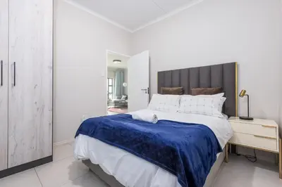 a white bedroom with a large bed and a mirror at Smartz Apartment in Erand