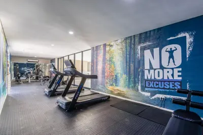 a gym with two tread machines and a no more excuses mural at Smartz Apartment in Erand