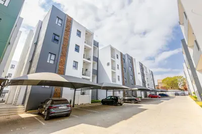 a building with cars parked in a parking lot at Smartz Apartment in Erand