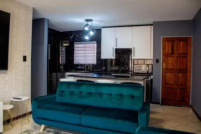 a living room with a couch and a kitchen at Time Oon-Travel & Tour Equestria Parkview in Pretoria
