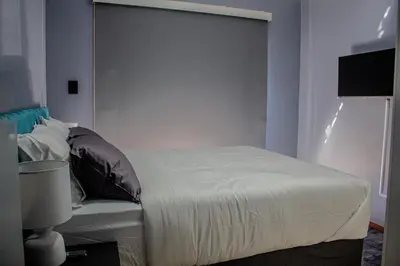 a bedroom with a white bed with a headboard at Time Oon-Travel & Tour Equestria Parkview in Pretoria
