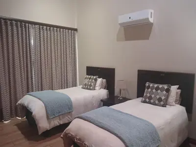 a bedroom with two beds and a window at Zebula Golf and Wildlife Estate - Bushveld Bliss Pax 14 - Moi Signature Luxury villa in Mabula