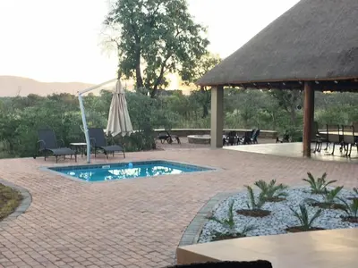 a swimming pool with an umbrella and tables and chairs at Zebula Golf and Wildlife Estate - Bushveld Bliss Pax 14 - Moi Signature Luxury villa in Mabula