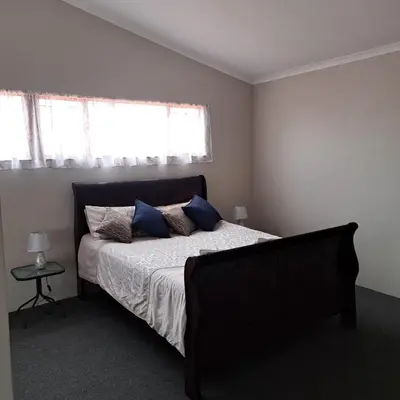 a bedroom with a bed with blue pillows and a window at Villa Tehillah in Dullstroom