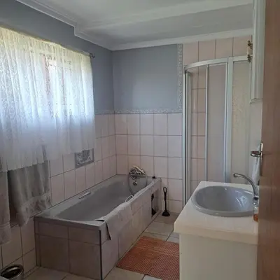 a bathroom with a tub and a sink at Villa Tehillah in Dullstroom