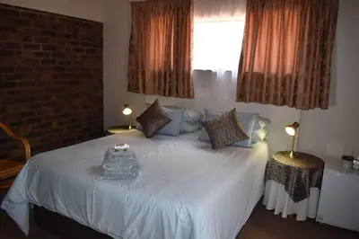 a bedroom with a large white bed with two lamps at Villa Tehillah in Dullstroom