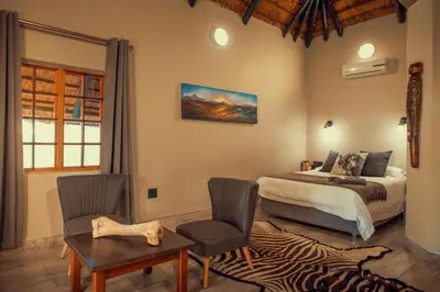 a bedroom with a bed and a table and chairs at Hayoma Lodge in Tshipise