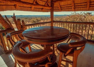 a wooden table and chairs on a balcony with a view at Hayoma Lodge in Tshipise