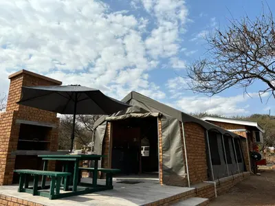 a tent with a table and an umbrella at Vrede Luxury Tented Camp in Kosmos