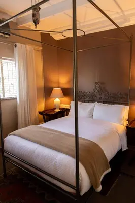 a bedroom with a large bed with a four poster bed at Camellia Luxury Apartment in Pretoria
