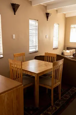 a dining room with a wooden table and chairs at Camellia Luxury Apartment in Pretoria
