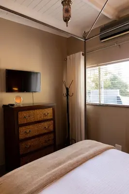 a bedroom with a bed and a dresser and a television at Camellia Luxury Apartment in Pretoria