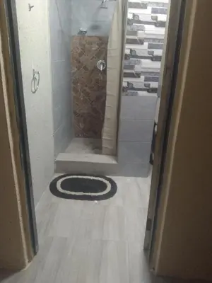 a bathroom with a shower with a rug on the floor at PK house in Mbabat